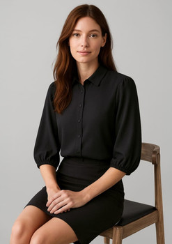 A black 3/4 sleeve blouse with a collared neckline, styled with a fitted skirt, displayed on a seated model.