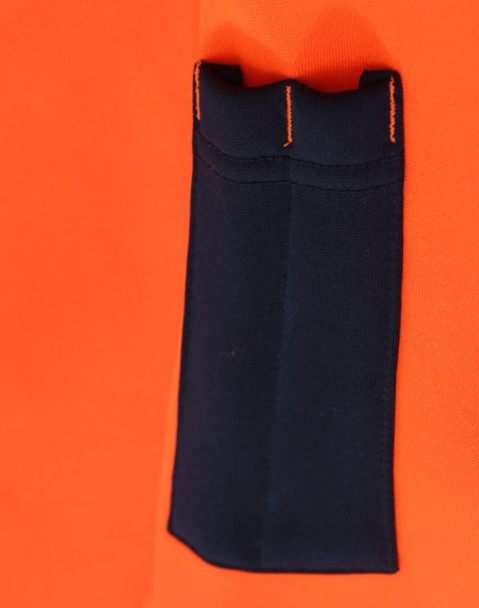 A close-up of a bright orange fleece hoodie featuring a navy blue pocket and contrasting stitching. It has a logo.