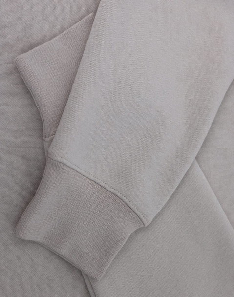 A light grey crewneck sweatshirt with a soft texture, featuring long sleeves and a cuffed hem.
