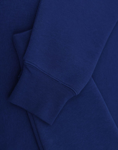 A blue crewfleece jumper featuring a close-up of the sleeve and cuff details. It has a small logo.