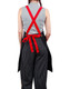 A black canvas bib apron with red straps worn over striped pants, featuring a tied waist and a logo on the back.