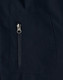 A close-up of a navy softshell jacket featuring a zippered pocket. The fabric appears smooth and durable.