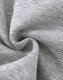 A close-up of soft, grey fabric with a slight texture, typical of a fleece jumper. It features a logo.