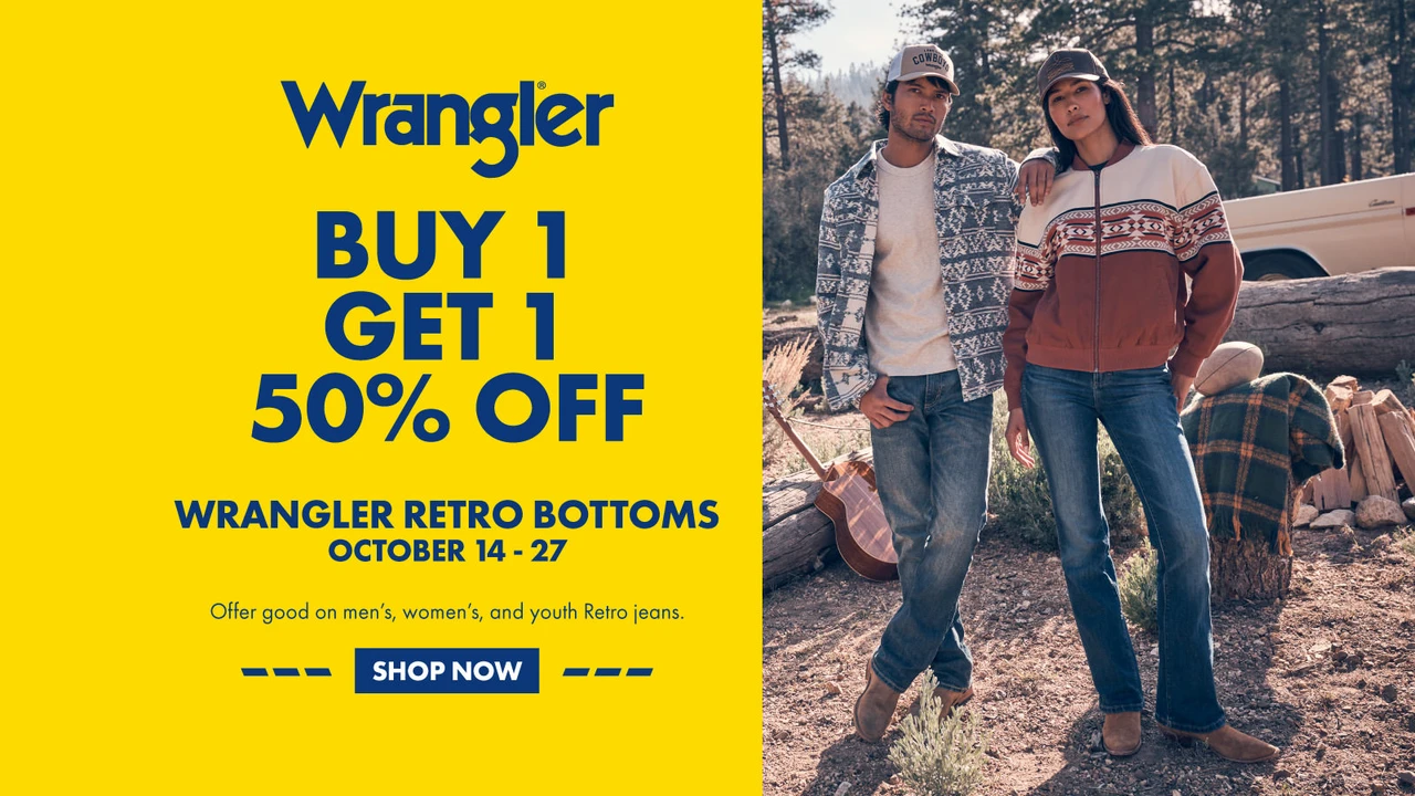 Click here to shop Wrangler Retro bottoms: Buy one, get one 50% off, October 14–27. Offer good on men’s, women’s, and youth Retro jeans. Shown with a man and woman in Wrangler jeans and western-pattern layers at a wooded campsite.