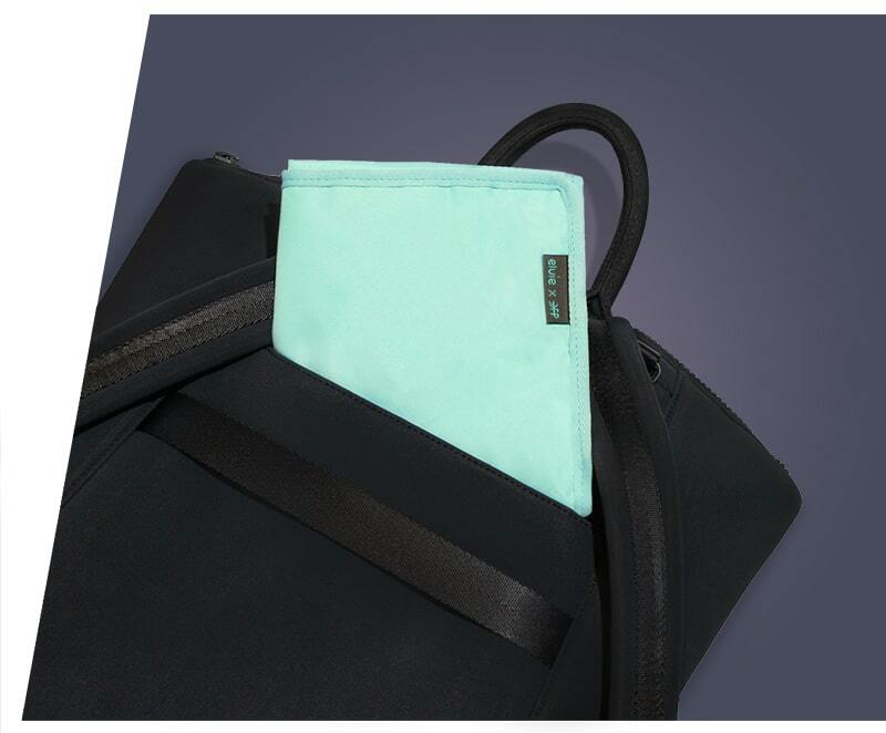 The black Elvie rucksack laid on its front, so the back with the straps is visible. There is a small zip pocket on the back and a mint green pouch is half inside the pocket
