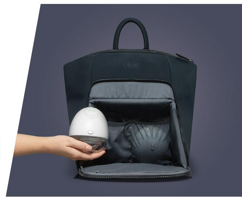 The Elvie black rucksack seen from the front. The front zip pocket is undone and open, showing two mesh pockets inside which each hold a breast pump. A woman's hand is holding an Elvie pump in front of the bag, while another pump is inside one of the mesh pockets