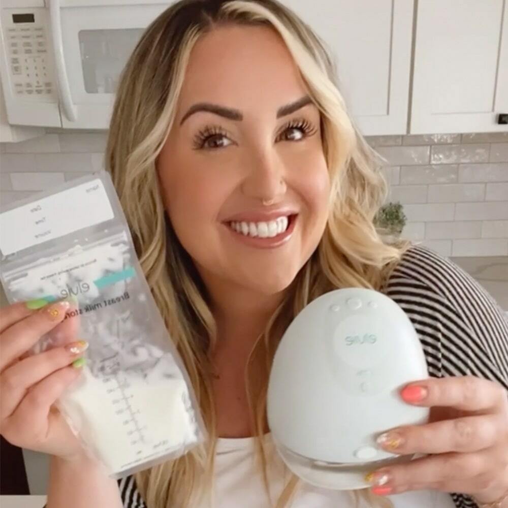 A woman holding an Elvie milk bag horizontally up to the camera