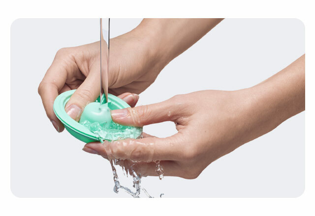 A close up of a woman's hands washing the silicone flange of an Elvie Stride under running water