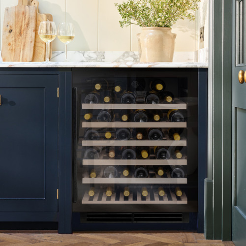 Black Glass Caple WI6143BG Sense Wine Cooler in a kitchen, packed with wine bottles and surrounded b