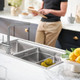 Person reading beside Caple Tayo Quad Kitchen Tap with lemons being washed in a steel sink