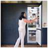 Woman using Caple RI7320 70/30 Fridge Freezer with opened door in a modern blue kitchen