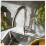Abode Sway Single Lever Kitchen Tap installed above a stainless steel sink near houseplants