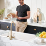 Man reading next to Caple Shaftsbury Kitchen Tap in a modern blue and marble kitchen.