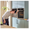 man looking through the viewing window if the Hotpoint SI4854HIX oven