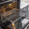 Caple Airfry2 Air Fry Tray in use, pulled halfway out of a oven in a classic blue and marble kitchen