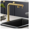 Abode Agilis Single Lever Kitchen Tap in brass over black sink with dishes in a modern grey kitchen