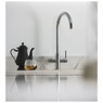 Black teapot and clear tea cup next to Abode Pronteau Prothia 3-in-1 Swan Kitchen Tap on counter