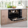 Caple C2902 Sense Electric Single Oven built into a wooden cabinet with open door showing dish insid