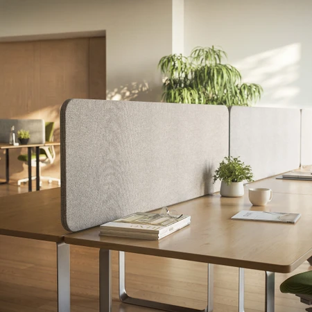 Sonus 25 pinnable fabric desk screen in light grey on a wooden bench desk in an open-plan office