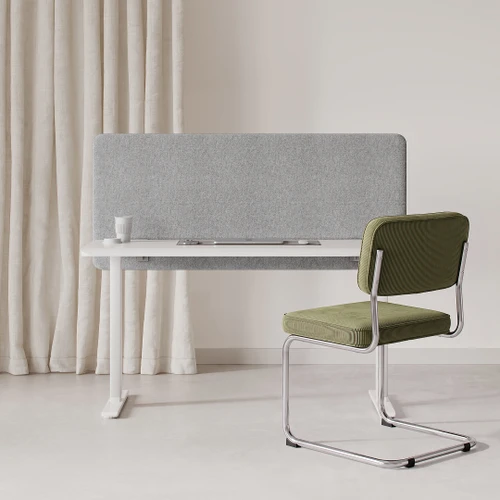 Grey acoustic desk divider and modesty panel on a white desk in an office