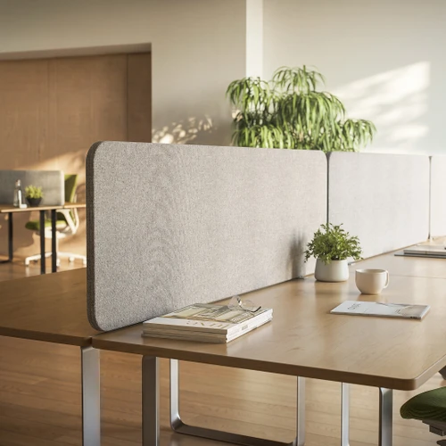 Sonus 25 pinnable fabric desk screen in light grey on a wooden bench desk in an open-plan office