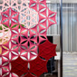 The Abstracta Airflake acoustic screen introduces functionality in style - dark pink open blade panels, light pink open line panels and red closed line panels - front view - in office.