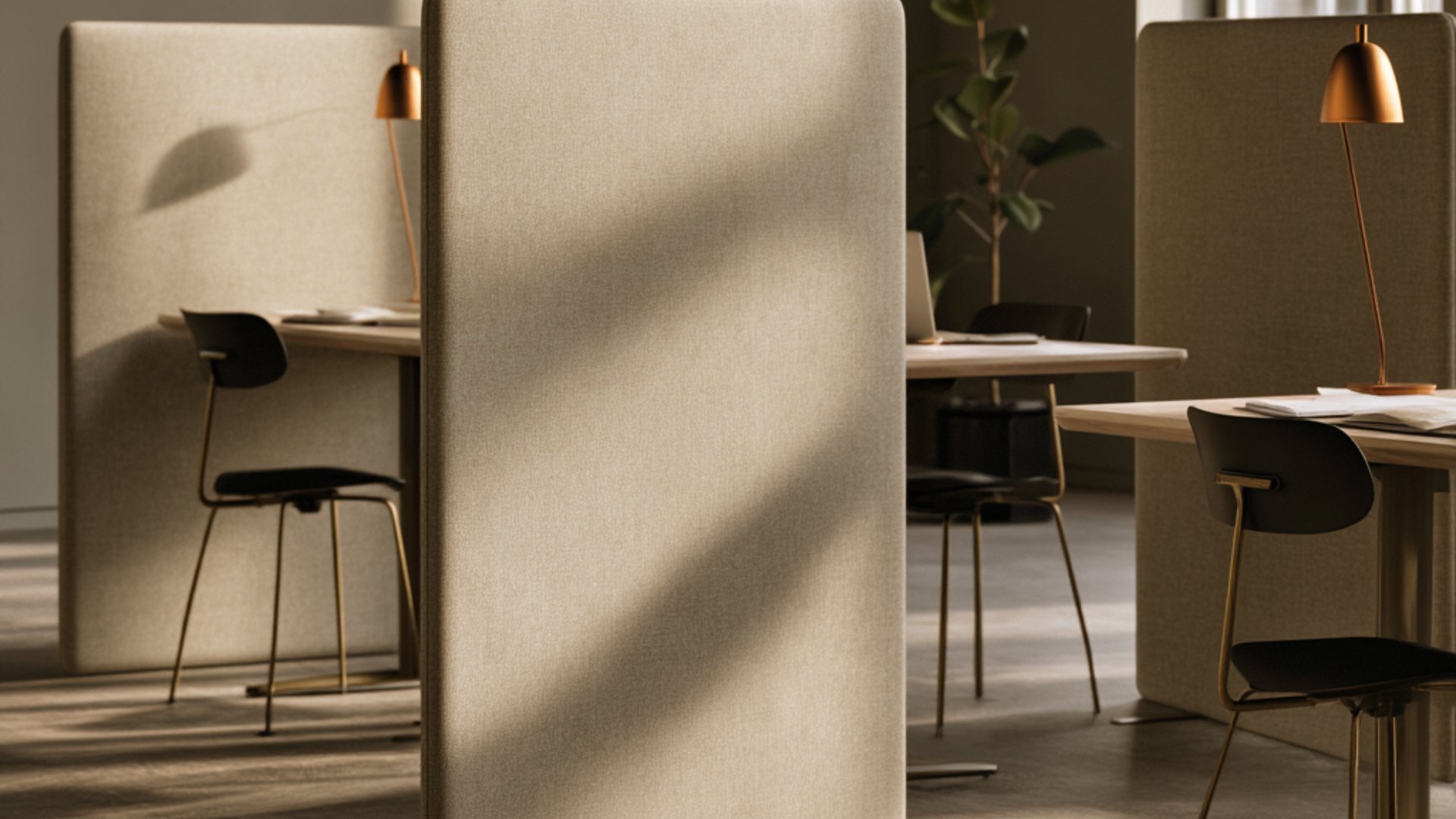 Beige fabric freestanding acoustic screens dividing desks in a sunlit office