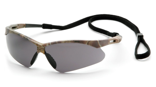 A high-definition 3/4 view of the Pyramex PMXTREME SCM6320STP safety glasses, featuring a forest camouflage frame paired with a smoke gray anti-fog lens. The gray lens is optimized for bright outdoor light to reduce glare and eyestrain, while the high-performance anti-fog coating ensures clear vision during temperature changes or high-exertion tasks. These glasses feature the signature PMXTREME 10-base curve panoramic lens for maximum wraparound side protection and a wide field of vision. Designed for all-day comfort, the camo temples are ventilated for airflow and include a built-in rubber nose piece for a secure, non-slip fit. This 23.1-gram model is ANSI Z87.1-2020 high-impact certified and comes with an included black lanyard cord for added security.