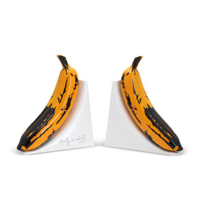 Image of 2 white bookends with large yellow bananas attached to each one, facing away from each other. Image of 2 white bookends with large yellow bananas attached to each one, facing away from each other.