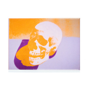 A rectangular magnet of an orange skull, purple shadow, sitting on a purple table. A rectangular magnet of an orange skull, purple shadow, sitting on a purple table.