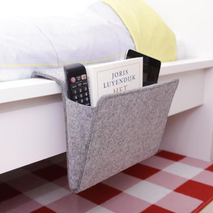 This image shows a grey bedside pocket hanging on the side of a bed.