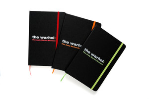 Three black journals spread out to show the different color text on each cover. text "The Andy Warhol Museum". Three black journals spread out to show the different color text on each cover. text "The Andy Warhol Museum".