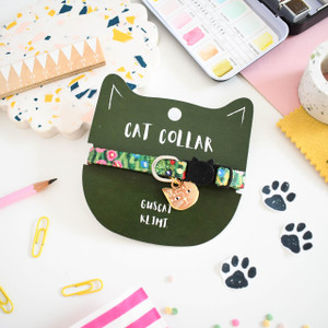 Green floral cat collar around green cat-shaped cardstock packaging. Featuring cat-shaped charm and buckle. Green floral cat collar around green cat-shaped cardstock packaging. Featuring cat-shaped charm and buckle.