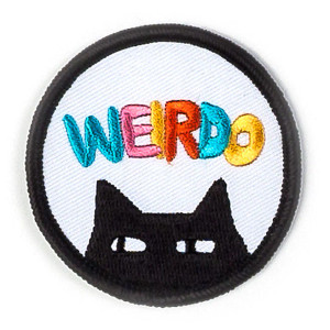 Round patch, black edge stitching, black cat peeking, text: "weirdo".