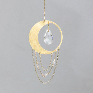 ornament with lunar motif, features one large crystal in center & three thin brass chains hanging from the bottom of a larger moon