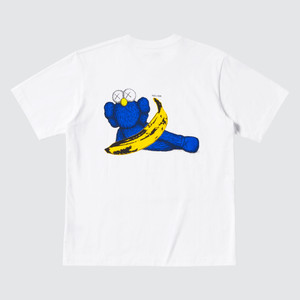 White tee, back view. KAWS Blue BFF, laying down sideways, holding a yellow Warhol banana. White tee, back view. KAWS Blue BFF, laying down sideways, holding a yellow Warhol banana.