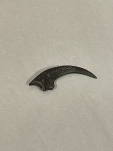 An image of the velociraptor killing claw replica. Dark in color, this measures two inches long.