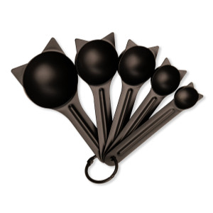 Five black cat shaped measuring spoons displayed on a white background. Five black cat shaped measuring spoons displayed on a white background.