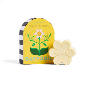 flower shaped pale yellow soap in front of it's box. the box is a rectangle with a rounded top edge and a drawing of a daffodil on the front. flower shaped pale yellow soap in front of it's box. the box is a rectangle with a rounded top edge and a drawing of a daffodil on the front.