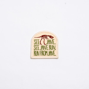 arch shaped patch, light beige background with a brown nanotyrannus at the top and "see jane, see jane run, run from jane" written in dark green