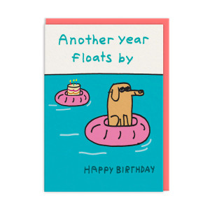 Dog on a floaty in a pool and a birthday cake on a floaty, text in black: Another years floats by Dog on a floaty in a pool and a birthday cake on a floaty, text in black: Another years floats by