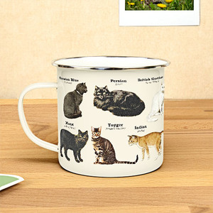 white metal mug with cats printed on it in front of a beige background white metal mug with cats printed on it in front of a beige background