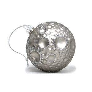 A glass ornament orb with craters painted with silver and glitter