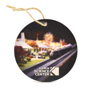 A round wooden ornament with a color-printed image of an O-Gauge model train in the Miniature Railroad & Village at the Kamin Science Center