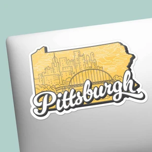 Sticker in the shape of Pennsylvania, yellow background with a skyline illustration, text is "Pittsburgh" written in white script.