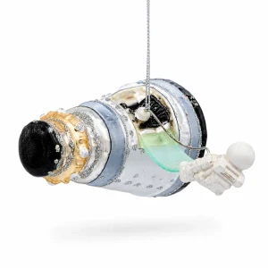A blown-glass ornament in the shape of a space capsule with a space-walking astronaut viewed at 3/4 from the front