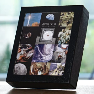 A display box containing a mission-flown fragment of the Apollo 8 Command Module with decorative photographs of the mission and crew