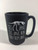 Black matte 12 oz ceramic mug imprinted in white fossil sandwiched between the text “ See Jane, See Jane Run, Run from Jane”.  With the Carnegie Museum of Natural History logo on the side.