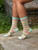 A person wearing a pair of socks with bright stripes and the phrase "Shhh I'm Over Thinking"