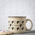 Cream-colored mug with pierogis and speckles scattered about.  "Pierogi"
